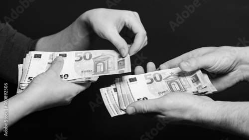 People count money, counting euro bills by man and woman, money on black background.