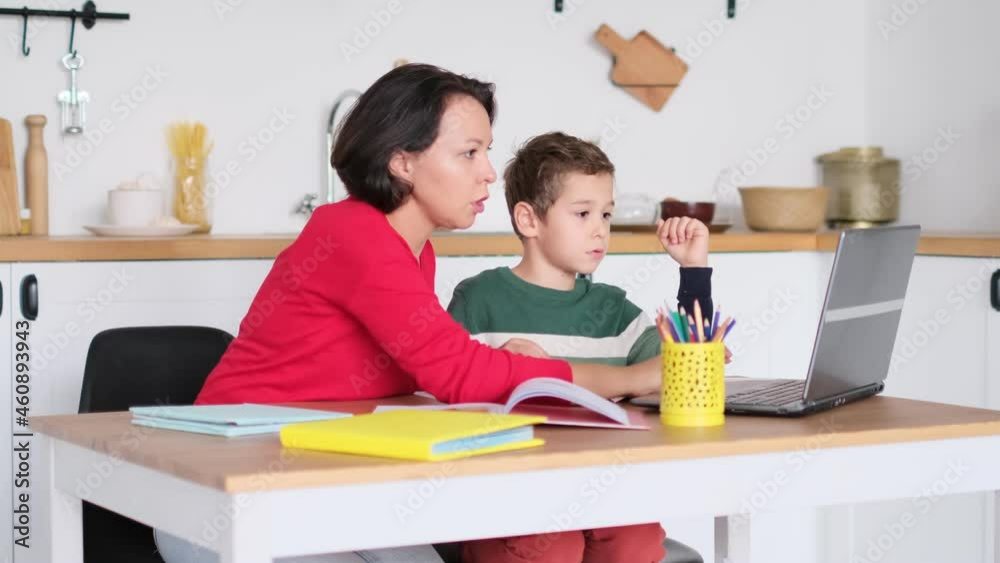 Female private tutor helping young student with homework at desk in bright child's room. mother helps son to do lessons. home schooling, home lessons. Female private tutor helping young student with homework at desk in bright child's room. mother helps son to do lessons. home schooling, home lessons.