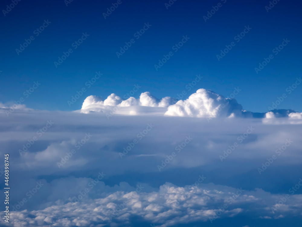 Obraz premium View from an airplane porthole to the beautiful white clouds and clear blue sky