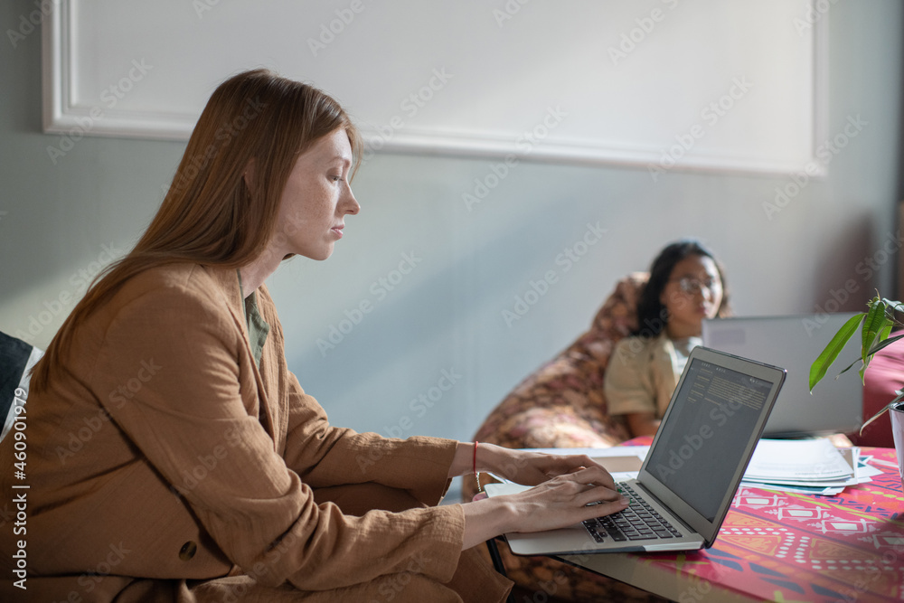 Young businesswoman networking in front of laptop in office against female co-worker Young businesswoman networking in front of laptop in office against female co-worker