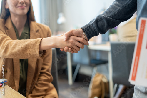 Handshake of two young successful office workers against workplace
