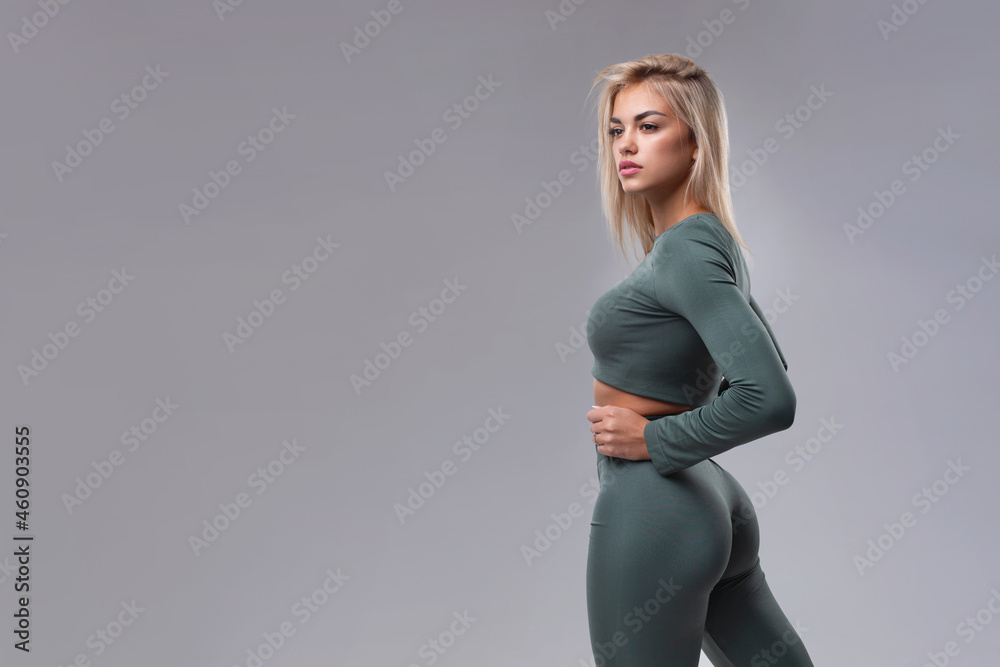 Studio portrait of a beautiful girl with big buttocks in sportswear on a  gray background. Photos | Adobe Stock