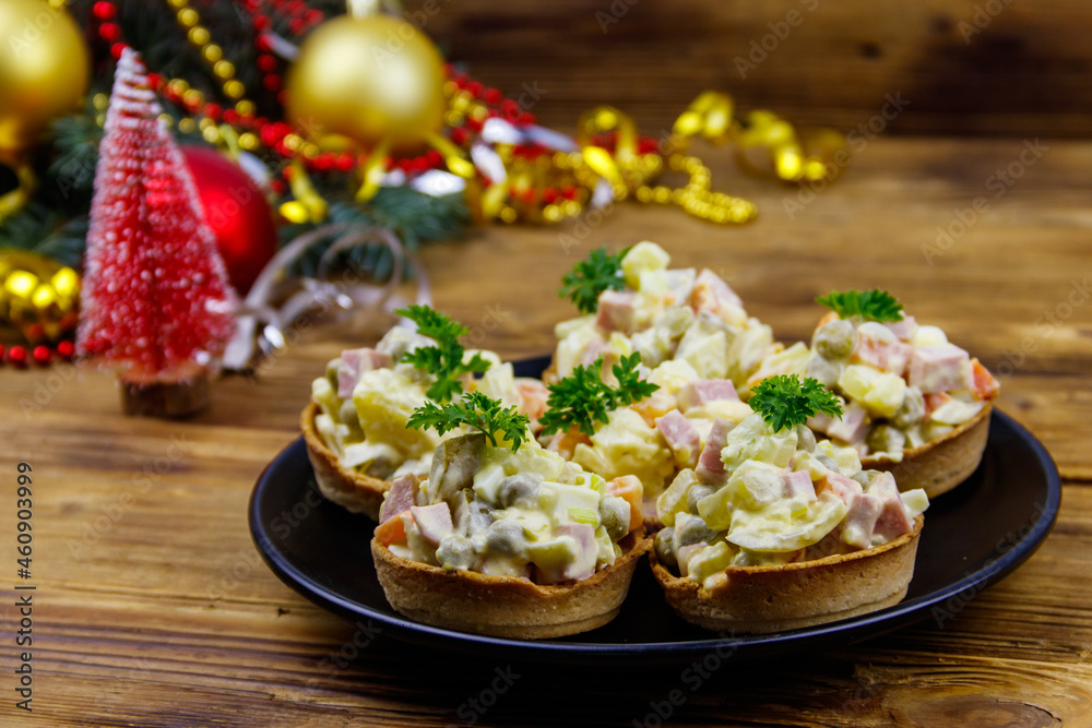 Traditional Russian festive salad Olivier in tartlets and Christmas decorations on wooden table