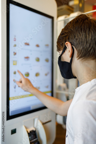 Fototapeta Naklejka Na Ścianę i Meble -  Teenage boy looking through menu at fast food restaurant