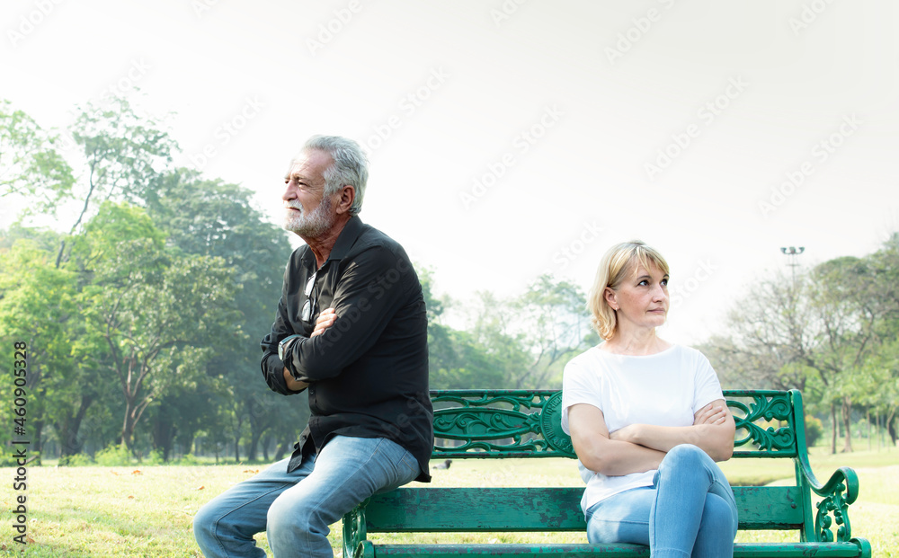 Offended mature man and woman sitting on different sides of bench outdoors at park. Old man and his wife ignoring and not speaking each other after conflict or fight. Relationship problems and upset. Offended mature man and woman sitting on different sides of bench outdoors at park. Old man and his wife ignoring and not speaking each other after conflict or fight. Relationship problems and upset.