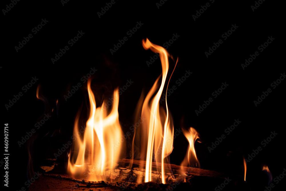 Fire in the fireplace on a dark background. Firewood in flames. An intimate atmosphere by the fire.