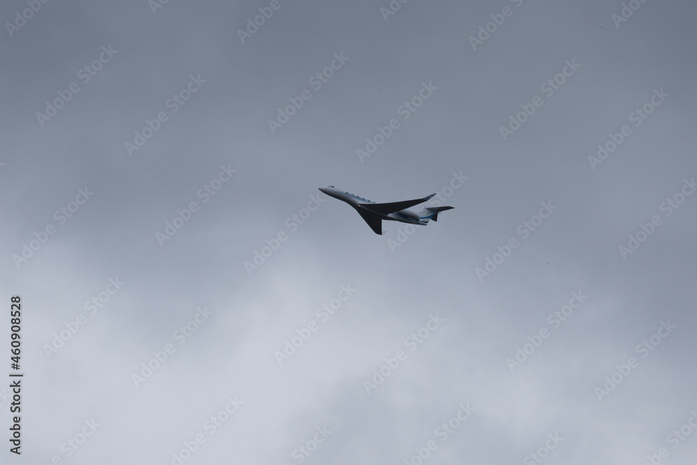 Silhouette of private Jet up in the sky against dark gray clouds Silhouette of private Jet up in the sky against dark gray clouds
