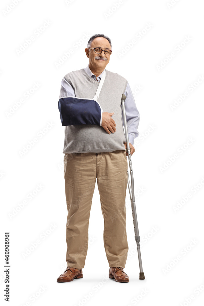 Full length portrait of a mature man with a broken arm wearing a splint and standing with a crutch Full length portrait of a mature man with a broken arm wearing a splint and standing with a crutch