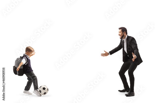 Full length profile shot of a schoolboy playing football with his father