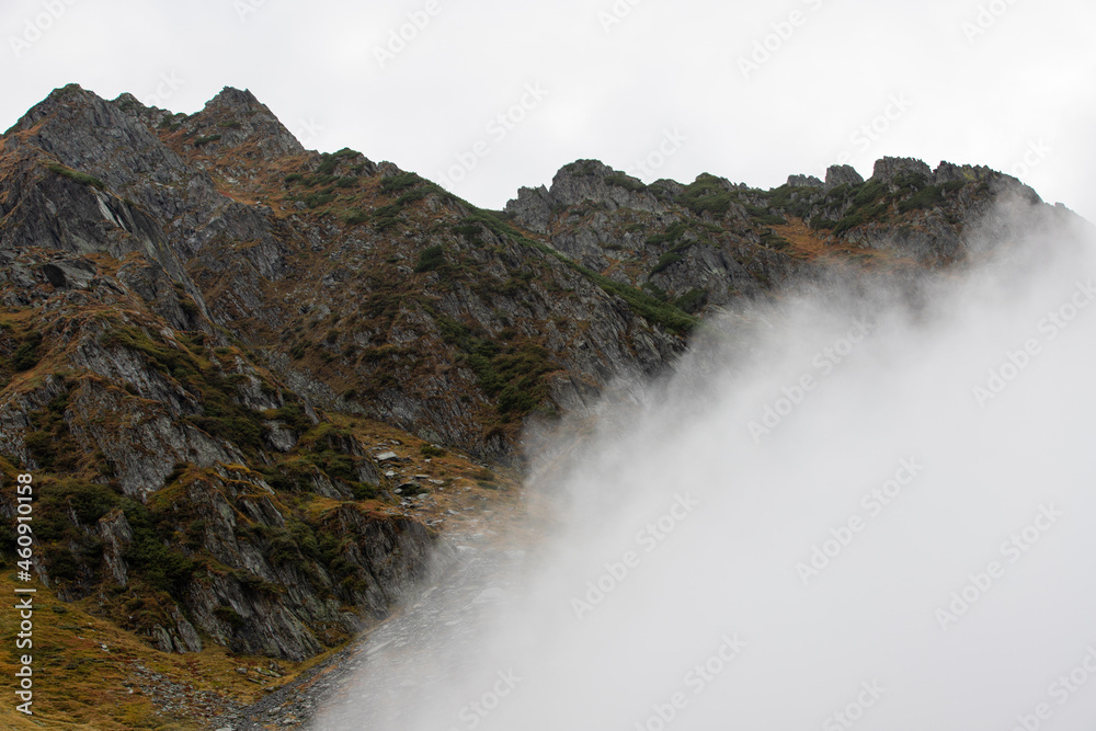 Fototapeta premium a mountain ridge emerging from the layer of clouds
