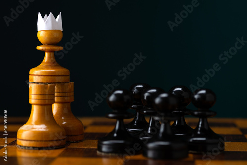 The concept of strategy and business planning, a white pawn in a paper crown in a paper crown against an army of black pawns, strategy and tactics, ready for battle