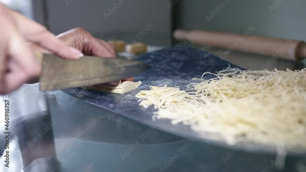 a woman cuts homemade noodles in close-up. a woman cuts homemade noodles in close-up.