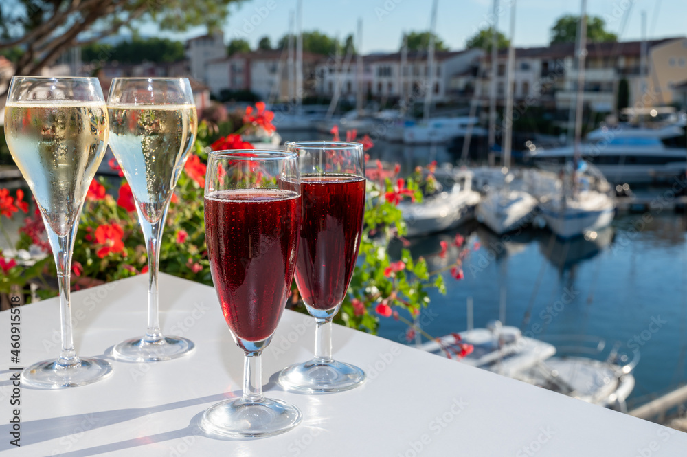 Summer party with kir royal cocktail, tasting of French brut champagne sparkling wine and cold creme cassis in glasses in yacht harbour of Port Grimaud near Saint-Tropez Summer party with kir royal cocktail, tasting of French brut champagne sparkling wine and cold creme cassis in glasses in yacht harbour of Port Grimaud near Saint-Tropez