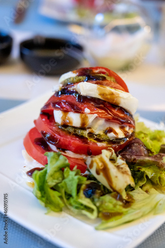 Big red french tomato served with fresh mozzarella cheese, basil pesto and creme balsamico as starter in restaurant in Provence, France