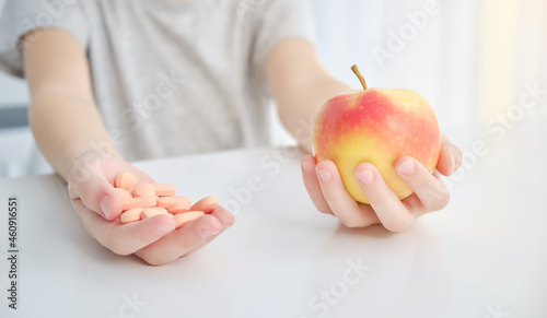 Apple and pills in hands. Natural vitamins concept.