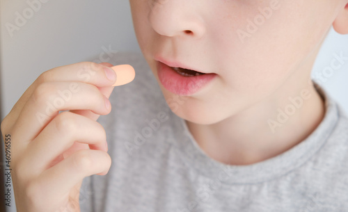 The boy puts the pill into his mouth. Close-up Photos