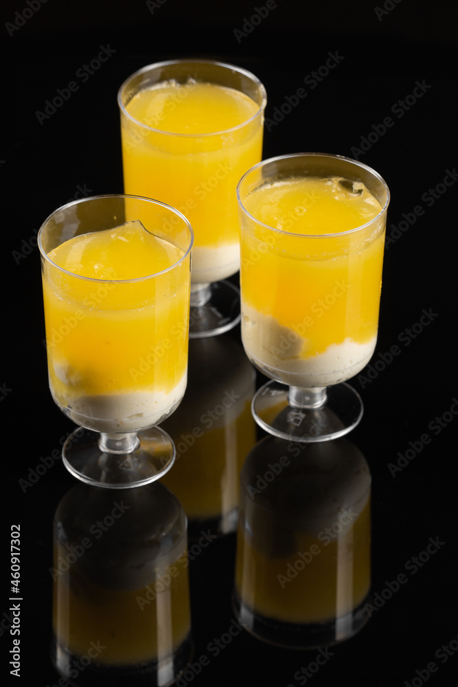 Yellow trifle cakes in glass on the black background Yellow trifle cakes in glass on the black background