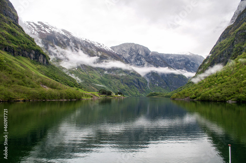 Sognefjord, Norway - 21 May 2016: View from the boat on the water in a deep valley (fjord) around which rise high green hills and above them are clouds