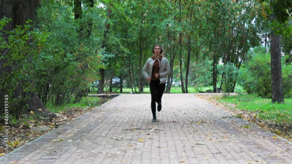A young girl is running in a city park. She stopped for a while to rest to catch her breath. She listens to music and wears headphones. A girl goes for a run in an autumn park. A young girl is running in a city park. She stopped for a while to rest to catch her breath. She listens to music and wears headphones. A girl goes for a run in an autumn park.