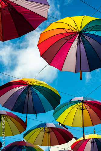 Umbrellas in rainbow colors hang from the sky 