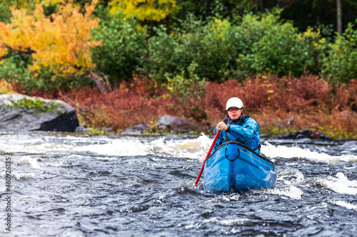 Fototapeta Naklejka Na Ścianę i Meble -  A solo canoeist practices stroke techniques on a rainy fall day as part of a “moving water” paddling course. Shot at Palmer Rapids on the Madawaska River an iconic paddling destination in Eastern Onta