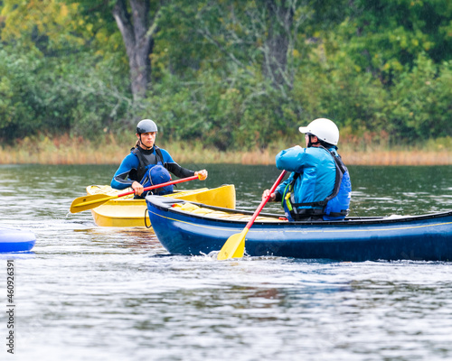 Two canoeists practice paddle strokes on a rainy fall day during a “moving water” paddling course.  At Palmer Rapids on the Madawaska River an iconic paddling destination in Eastern Ontario, Canada