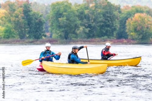 Three canoeists practice paddle strokes on a rainy fall day during a “moving water” paddling course.  At Palmer Rapids on the Madawaska River an iconic paddling destination in Eastern Ontario, Canada