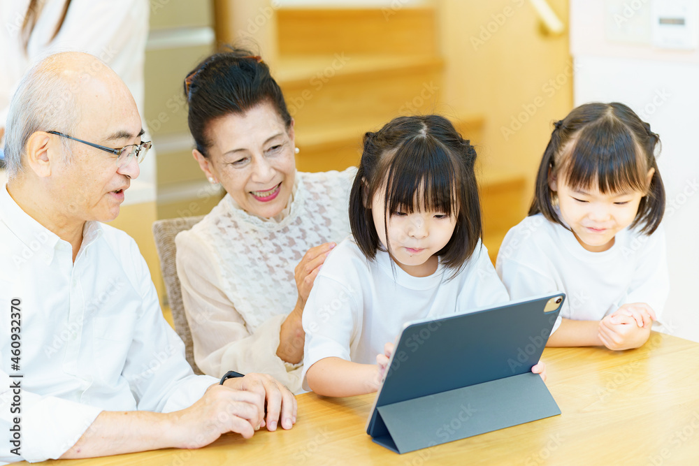 タブレットPCを操作するシニア夫婦と孫たち タブレットPCを操作するシニア夫婦と孫たち