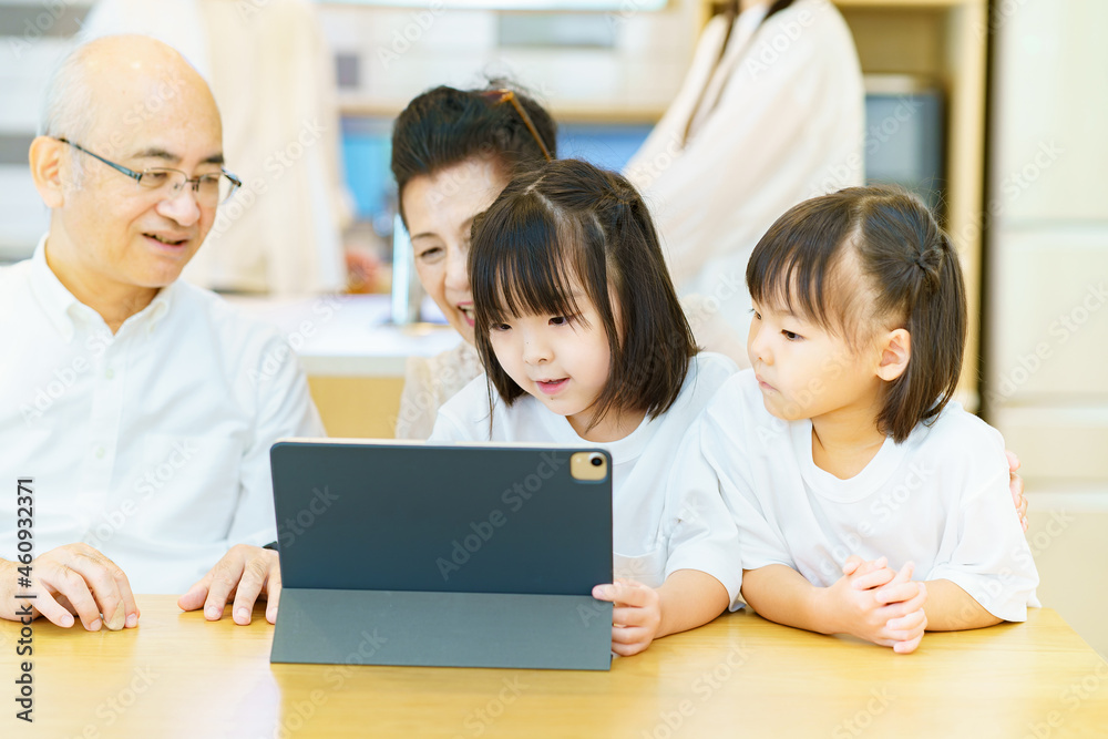 タブレットPCを操作するシニア夫婦と孫たち タブレットPCを操作するシニア夫婦と孫たち