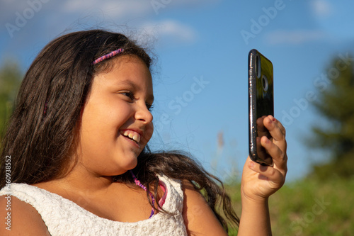 Fotografie gipsy girl with long black hair takes selfies with his smartphone