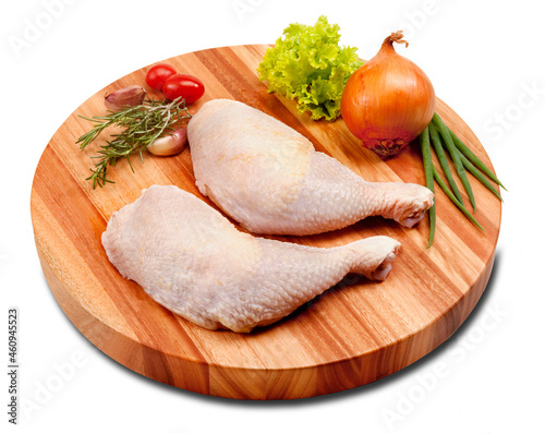 Coxa e sobrecoxa do frango crua, sobre tábua de madeira redonda no fundo branco para recorte. photo