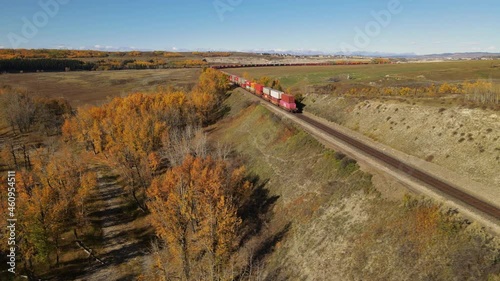 Freight train passes  in Cochrane, Canada. Canadian Pacific Railway Cargo train passes near the mountains and rivers in fall. Aerial View.