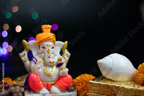 Murti or Moorti Of Hindu God Lord Ganesha Ganpati Bappa Morya In Orange Pagdi For Worship On Diwali Puja New Year Deepawali Ganesh Chaturthi Or Shubh Deepavali Pooja. Black Background With Copy Space photo