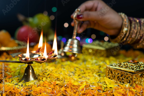 Panchmukhi Golden Brass Diya Deep lit On Flower Bed Decoration And Bokeh Effect For Diwali Puja New Year Deepawali Or Shubh Deepavali Navratra Pooja Festival Celebration. Women holding Bell Background photo