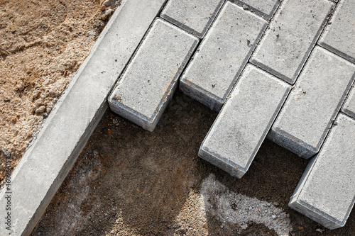 Pavement repair and laying of paving slabs on the walkway, stacked tile cubes on the background. Laying paving slabs in the pedestrian zone of the city, sand filling. Road tiles and curbs.