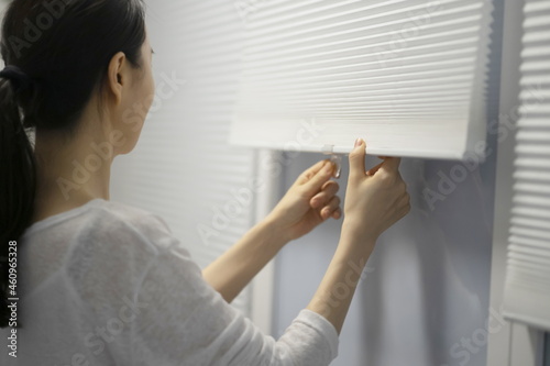 Close up of woman opening window blinds