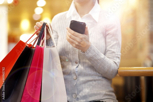 Woman carrying shopping bags and using smartphone