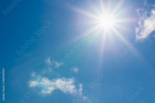 Shining sun at clear blue sky,clouds.Solar lens flare. copy space.Natural lens flare.Sunrays of bright sun on summer day. © ARVD73