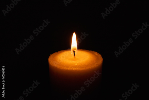 One single light candle burning brightly in the black background.Spiritual candle yellow flame. Flame of candle in the darkness.Copy space.