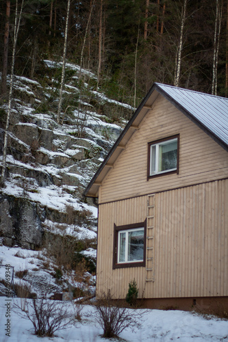 small wooden house by a cliff in the forest in winter