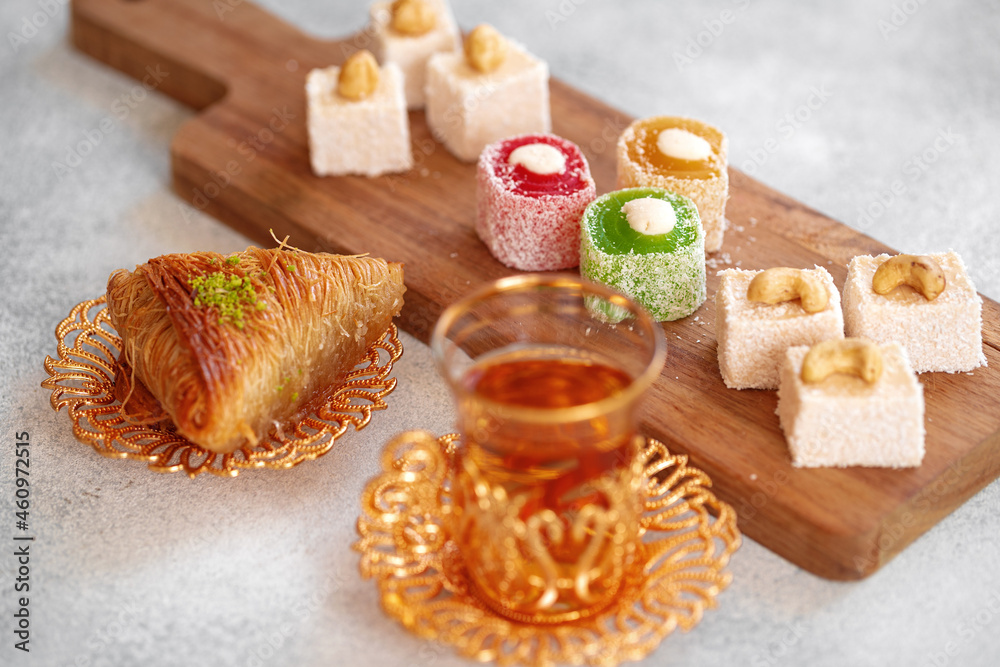 Fototapeta premium Various Turkish sweets and cup of tea on white textured background