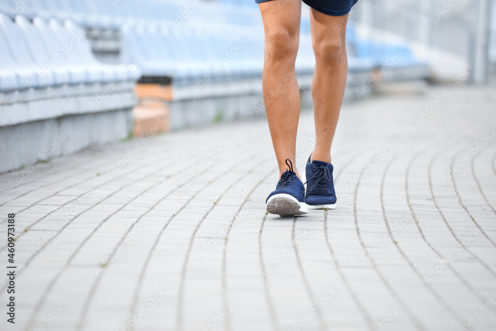 Legs of sporty young man walking at stadium Legs of sporty young man walking at stadium
