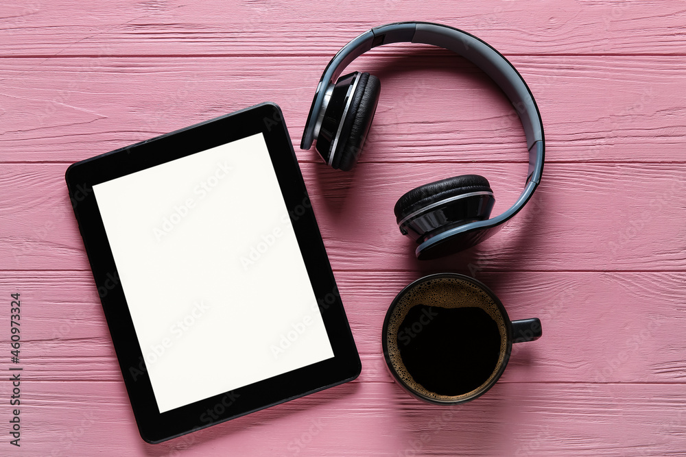 Modern tablet computer, cup of coffee and headphones on color wooden background Modern tablet computer, cup of coffee and headphones on color wooden background
