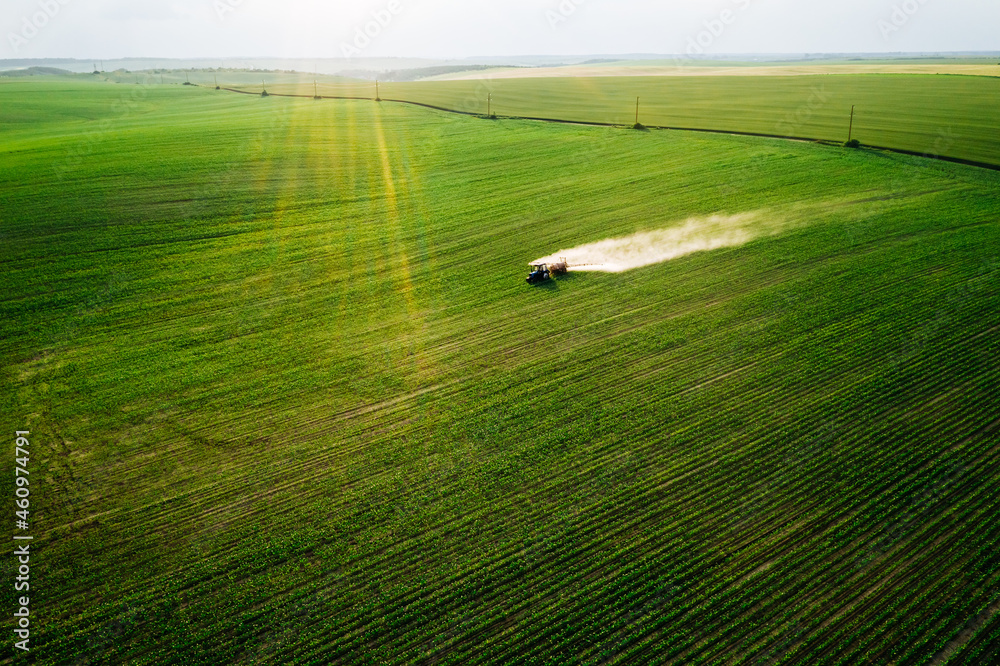 Scenic top view of a tractor spraying green fields. Scenic top view of a tractor spraying green fields.