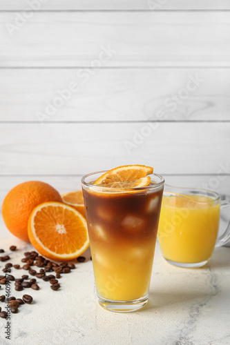 Glass of tasty coffee with orange juice on table