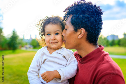 mixed race enjoy father carrying little african girl child smiling in summer park