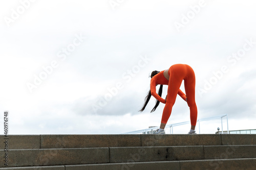 Young woman tired after running. Female athlete bending over catching her breath jogging.
