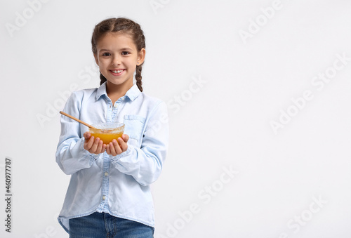 Little girl with honey on white background