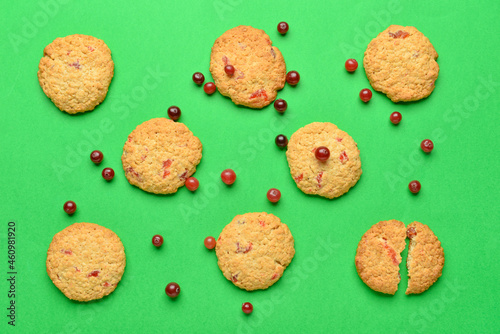 Delicious cranberry cookies and berries on green background