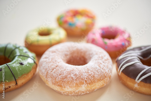 Close-up of sweet glazed donuts with various topping placed in shape of triangle